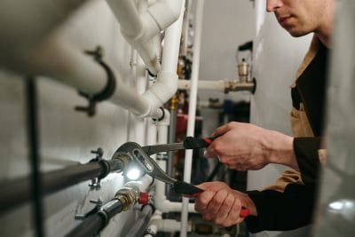 Technician inspecting commercial plumbing pipes in Carson