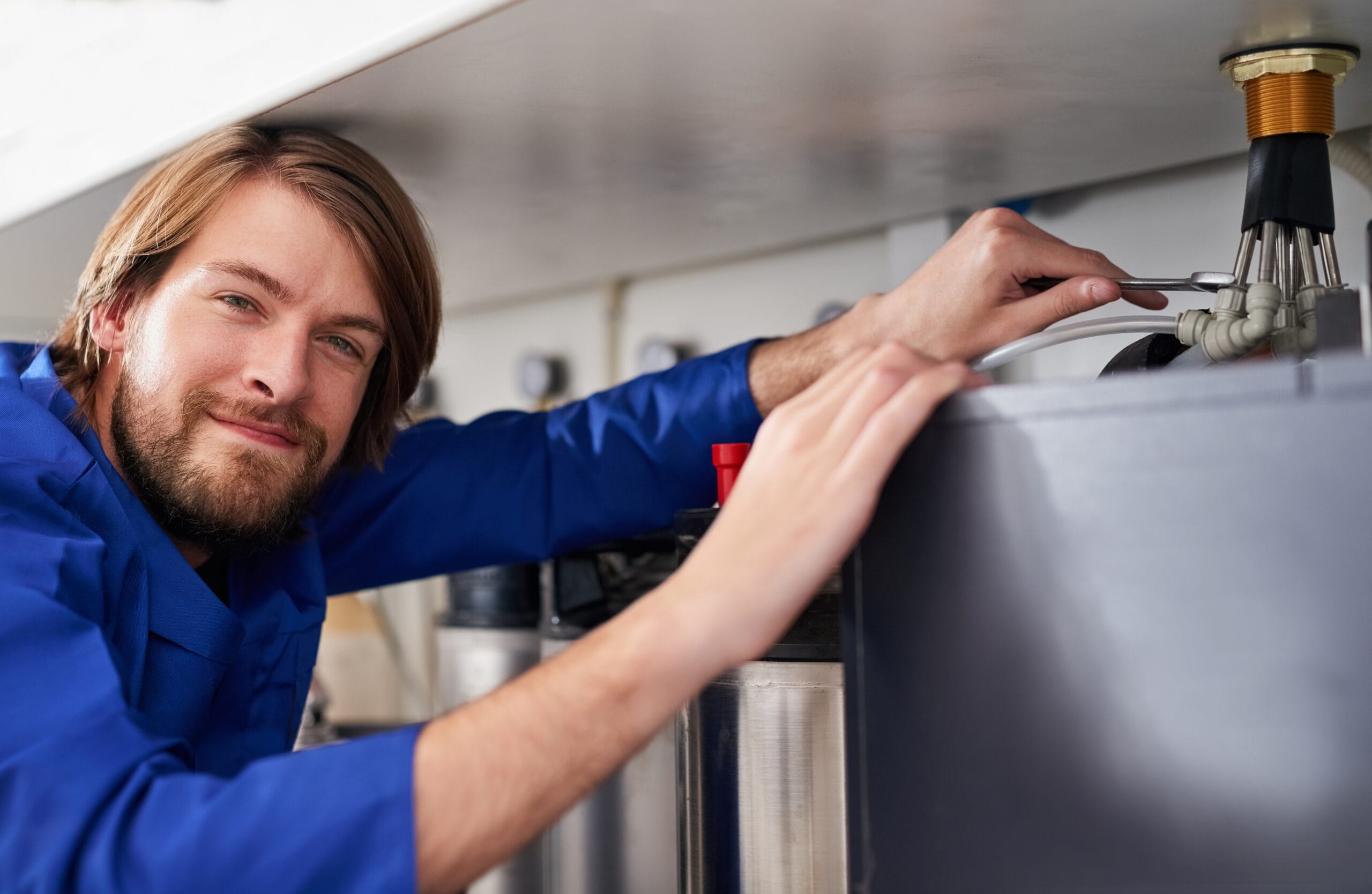 Technician servicing a residential water heater tank in Carson